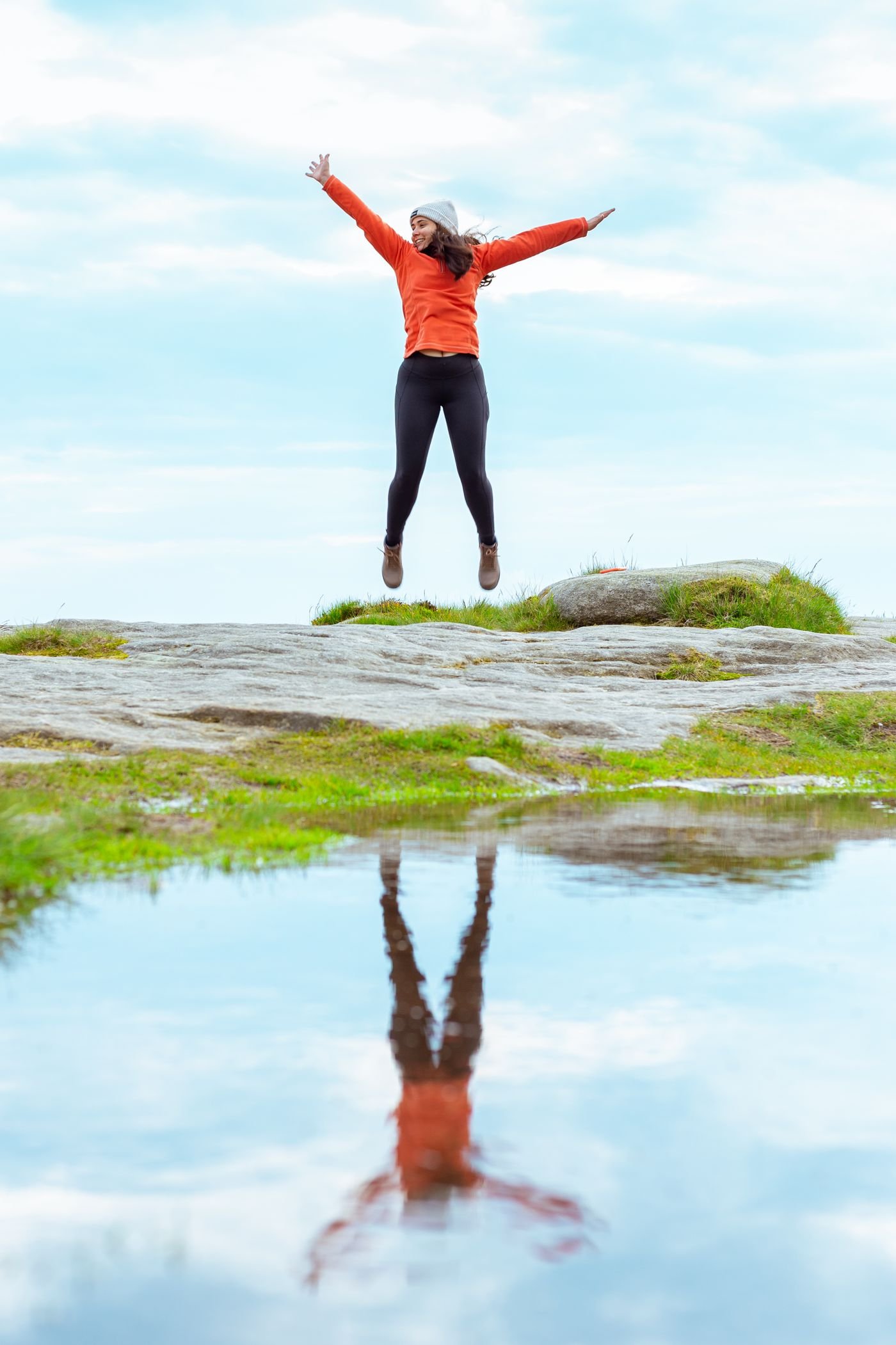 Woman in an orange jacket jumping with energy