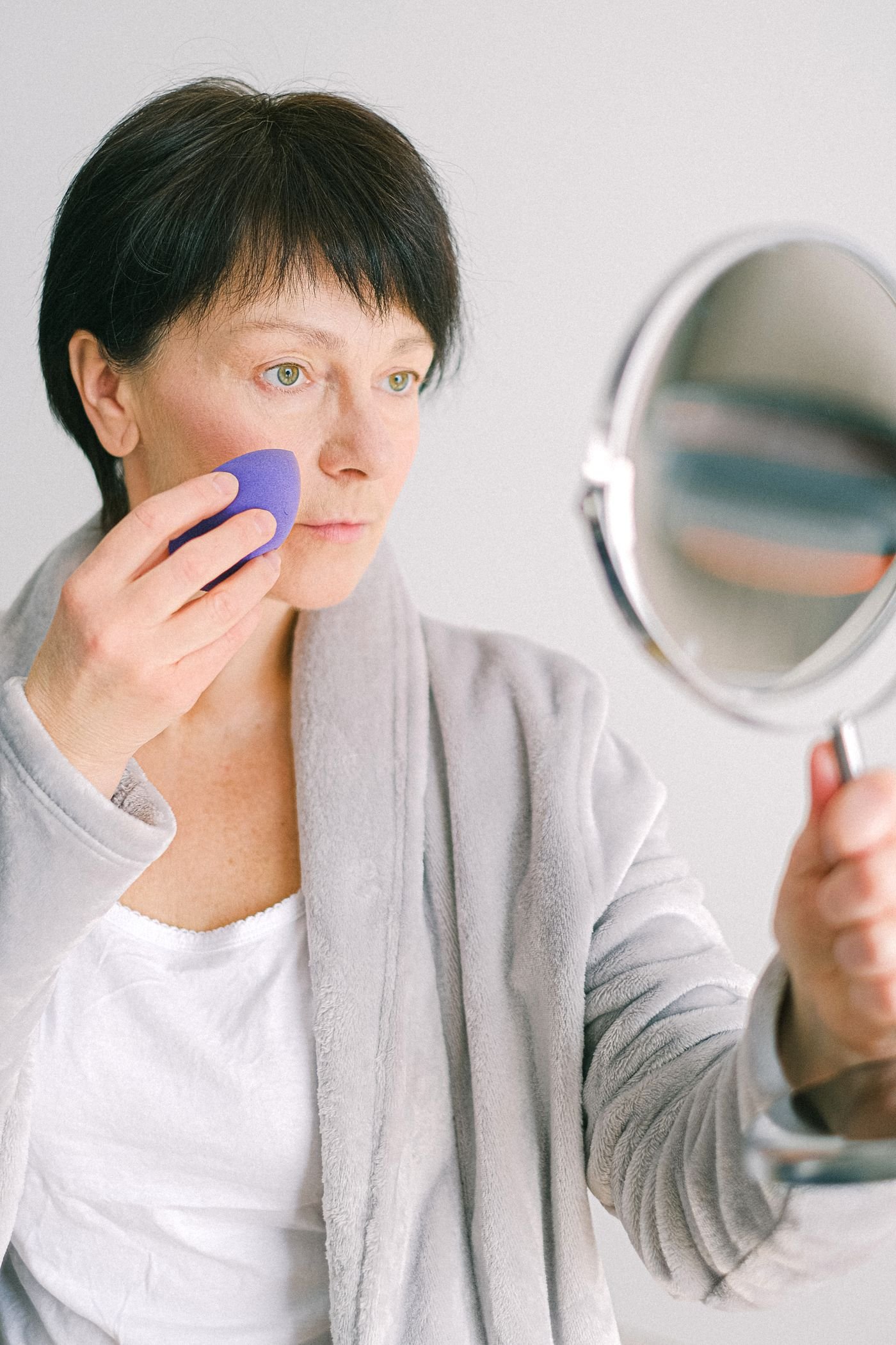 Close-up of a woman examining her glowing skin in a mirror
