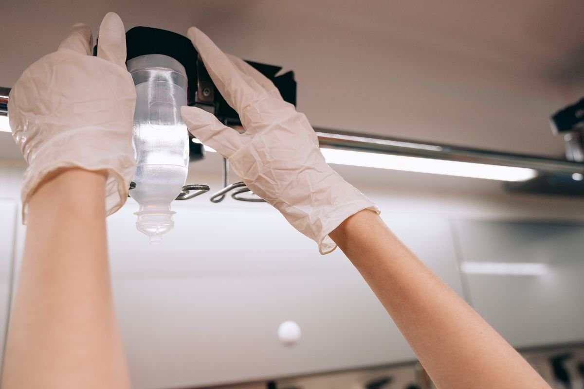 Gloved hands preparing an IV drip at The London Health and IV Clinic