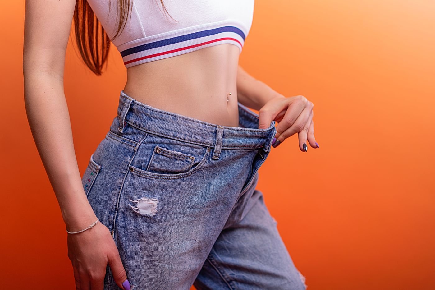 Woman in loose jeans showing weight loss